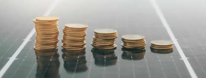 Pile de pièces de monnaie sur un fond de panneau solaire